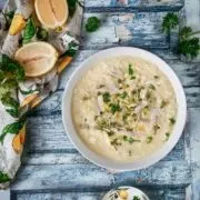 Sommersuppe mit Zitronen und Hähnchenfleisch und Reis auf einem blauen Tisch, dekoriert mit frischen Zitronen