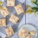 Apfelmus Streuselkuchen mit Puderzucker bestäubt auf einem blauen Holztisch mit gelben Blumen